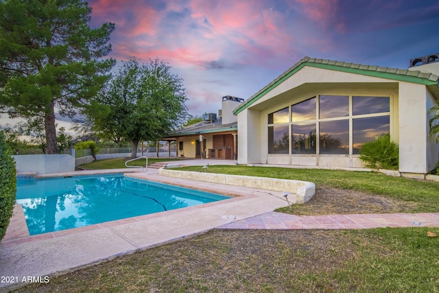 pool at dusk with a yard and a patio