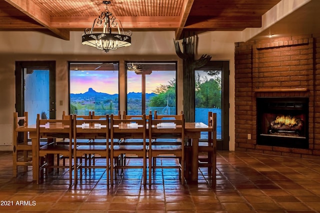 dining area featuring wood ceiling, a brick fireplace, a mountain view, a notable chandelier, and beamed ceiling