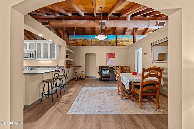 dining room featuring beamed ceiling, light hardwood / wood-style flooring, and wood ceiling