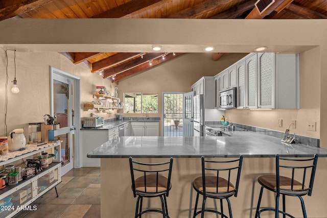 kitchen with white cabinetry, vaulted ceiling with beams, appliances with stainless steel finishes, and kitchen peninsula