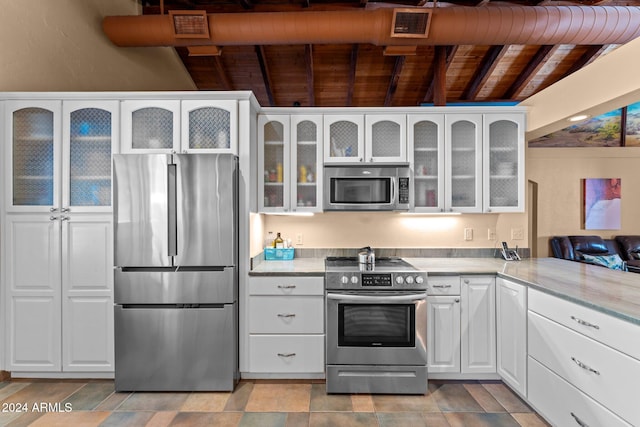 kitchen featuring beam ceiling, stainless steel appliances, wooden ceiling, white cabinets, and light stone counters