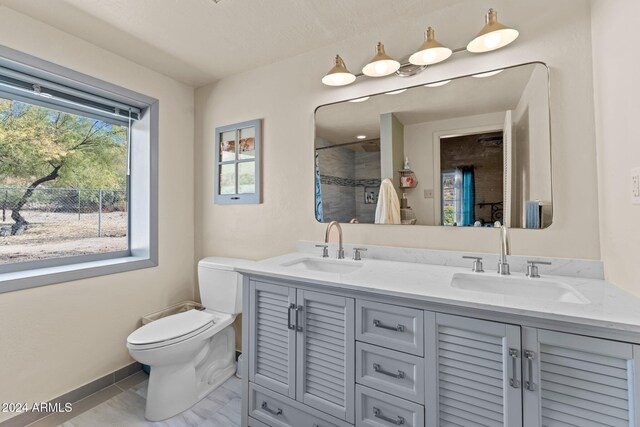 bathroom with toilet, vanity, and tiled shower