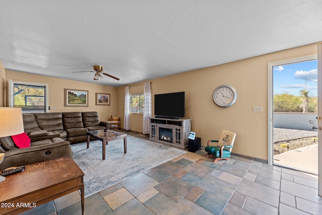 living room featuring a fireplace, a textured ceiling, and ceiling fan