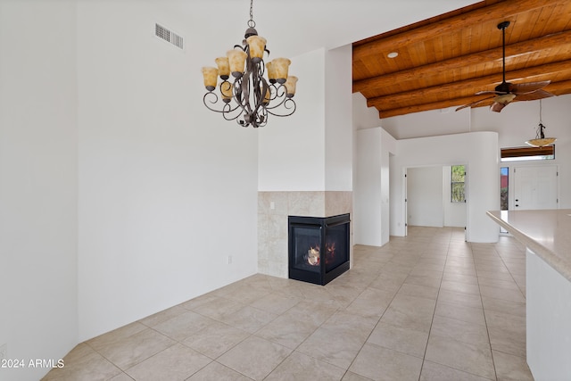 unfurnished living room with wood ceiling, ceiling fan with notable chandelier, beam ceiling, a tiled fireplace, and light tile patterned floors