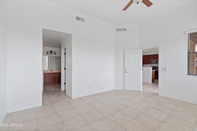 interior space featuring light tile patterned floors, ceiling fan, and ensuite bathroom