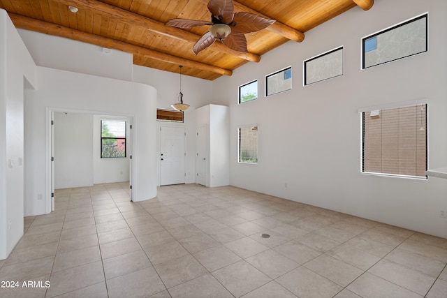 tiled empty room with ceiling fan, beamed ceiling, and wooden ceiling