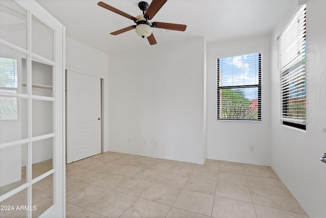 spare room with ceiling fan and light tile patterned floors