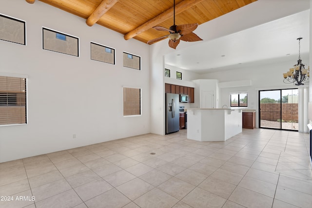 unfurnished living room with a high ceiling, beamed ceiling, ceiling fan with notable chandelier, light tile patterned floors, and wooden ceiling