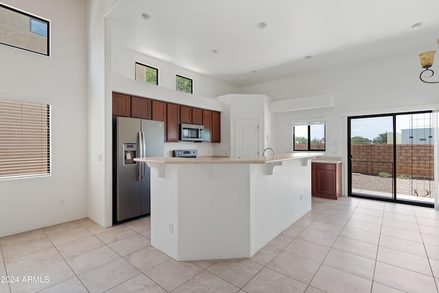 kitchen with a breakfast bar, light tile patterned floors, a center island with sink, and stainless steel appliances