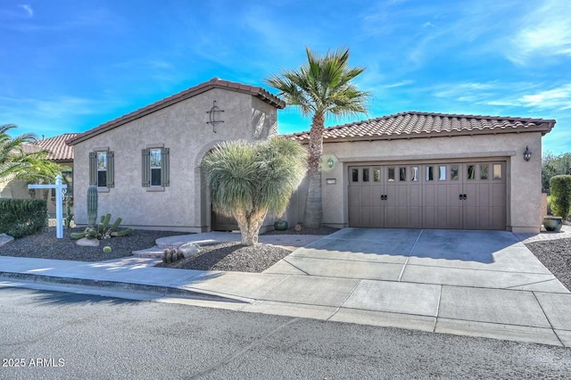 mediterranean / spanish home featuring a garage, concrete driveway, a tiled roof, and stucco siding