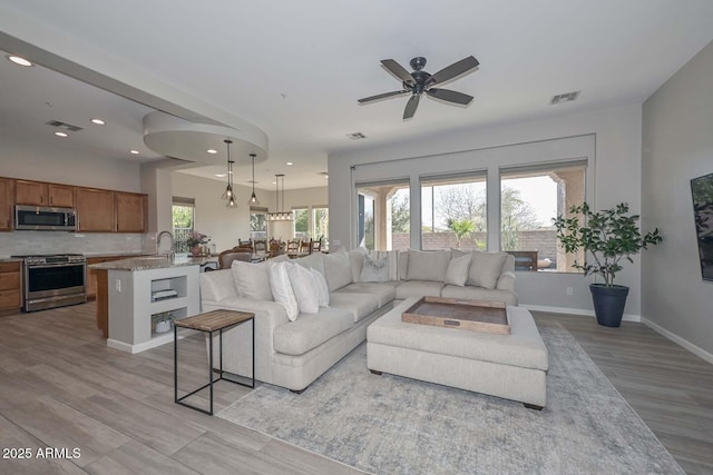 living room with recessed lighting, visible vents, light wood-style flooring, and baseboards