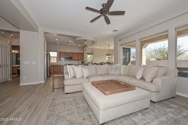 living area featuring baseboards, a healthy amount of sunlight, visible vents, and light wood-style floors