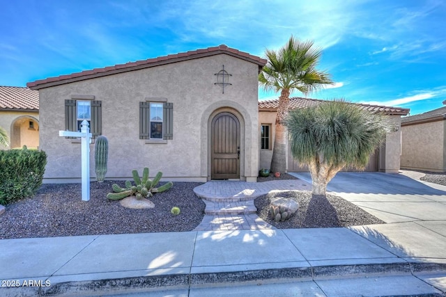 mediterranean / spanish-style home with a tiled roof, driveway, and stucco siding