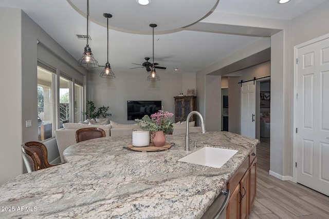 kitchen with pendant lighting, visible vents, a barn door, open floor plan, and a sink