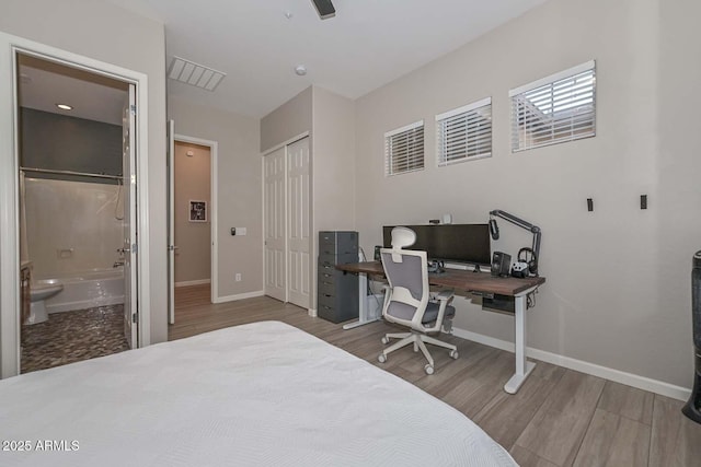 bedroom featuring wood finished floors, visible vents, baseboards, a closet, and ensuite bath