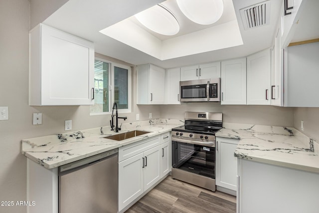 17228 N 16th Dr Unit 3, Phoenix, AZ 85023 - kitchen featuring appliances with stainless steel finishes, white cabinets, light wood-style flooring, and light stone countertops