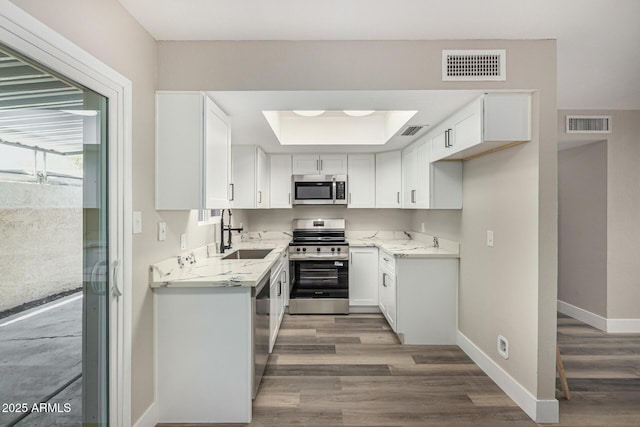 17228 N 16th Dr Unit 3, Phoenix, AZ 85023 - kitchen with stainless steel appliances, light wood-style flooring, white cabinetry, and light stone counters