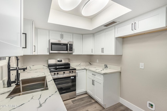 17228 N 16th Dr Unit 3, Phoenix, AZ 85023 - kitchen featuring stainless steel appliances, white cabinets, light wood-style flooring, and light stone counters