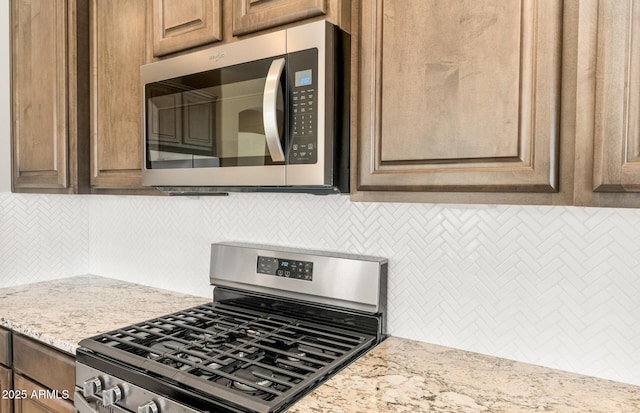 26949 W Lone Cactus Dr, Buckeye, AZ 85396 - kitchen view of appliances with stainless steel finishes, decorative backsplash, and light stone counters
