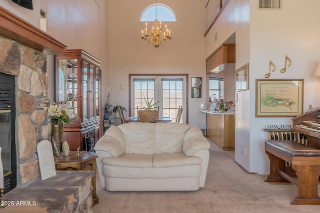 living area featuring light carpet, a towering ceiling, visible vents, and a chandelier