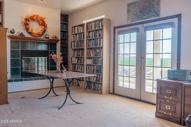 carpeted office space with french doors and a tiled fireplace