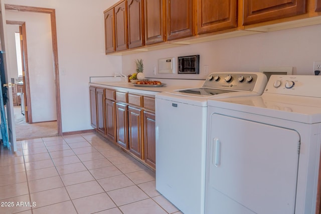 washroom with light tile patterned floors, a sink, baseboards, cabinet space, and washer and clothes dryer