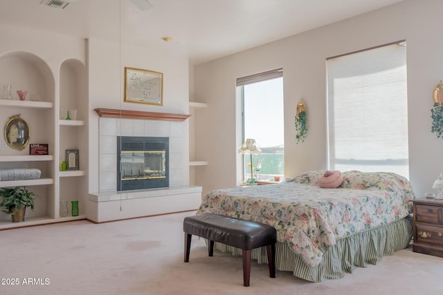 bedroom with a tile fireplace, visible vents, and carpet