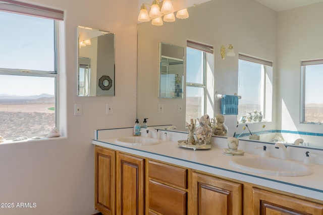 full bathroom with double vanity, a notable chandelier, and a sink