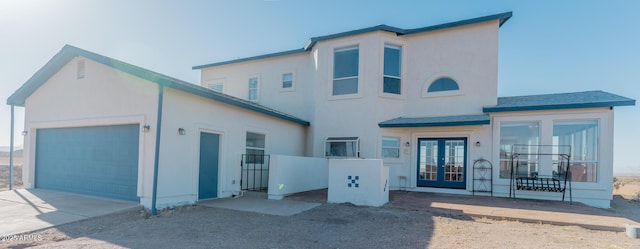 view of front of home featuring french doors, concrete driveway, an attached garage, and stucco siding