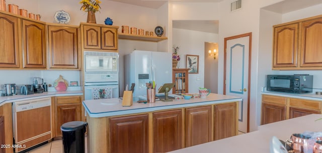 kitchen featuring light countertops, white appliances, visible vents, and brown cabinets