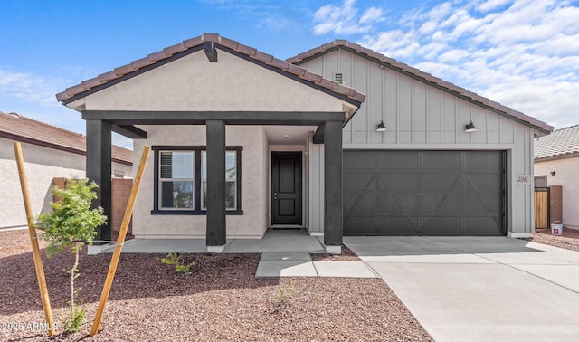 view of front of property featuring board and batten siding, stucco siding, a tiled roof, driveway, and an attached garage