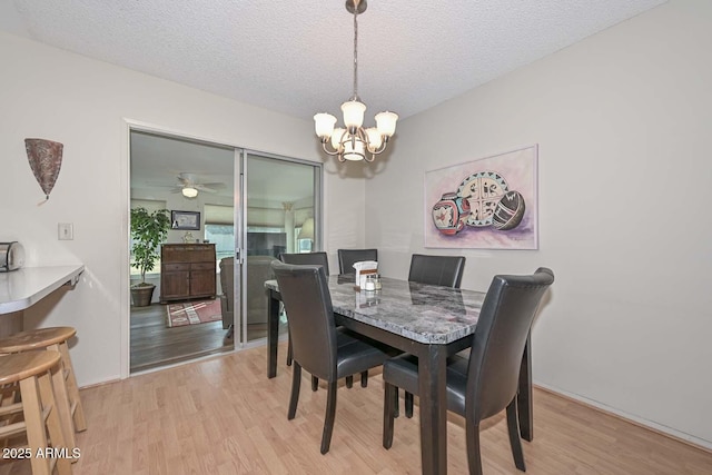 dining area with an inviting chandelier, light hardwood / wood-style floors, and a textured ceiling