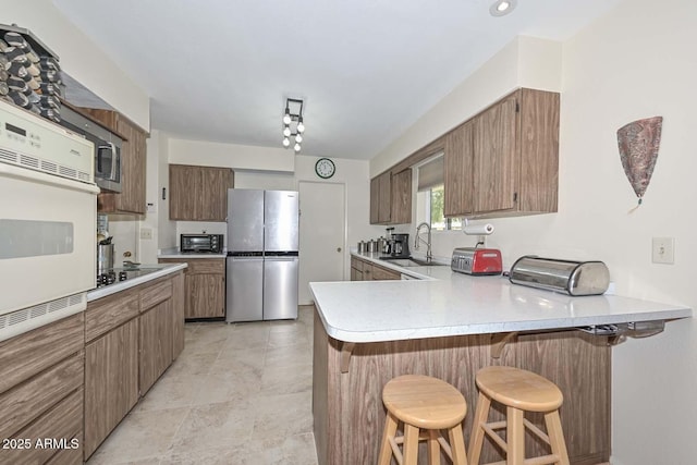 kitchen featuring sink, a kitchen breakfast bar, appliances with stainless steel finishes, and kitchen peninsula