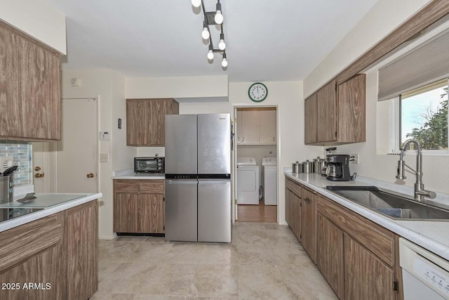 kitchen featuring sink, separate washer and dryer, white dishwasher, and stainless steel refrigerator