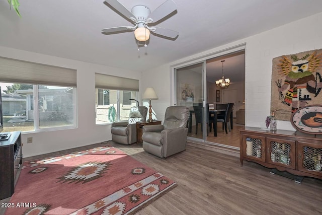 living room with ceiling fan with notable chandelier and hardwood / wood-style floors