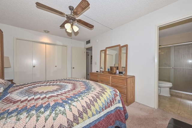 carpeted bedroom with a textured ceiling, a closet, ensuite bath, and ceiling fan