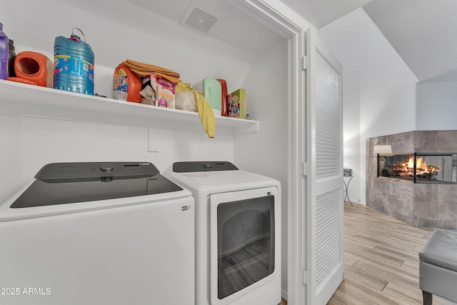 clothes washing area with a tile fireplace and washing machine and clothes dryer