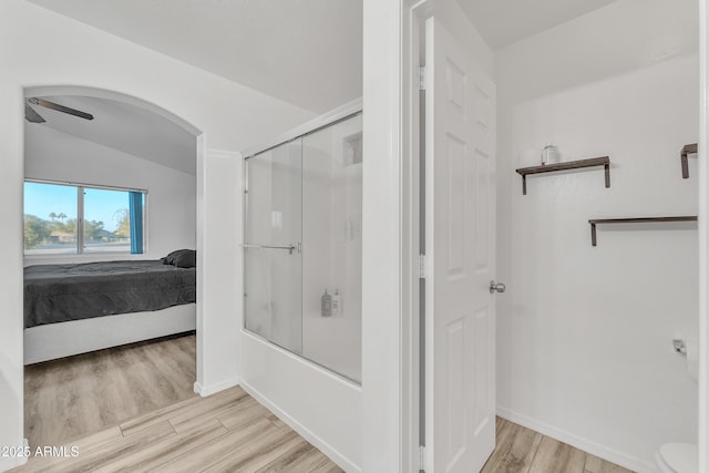 bathroom with vaulted ceiling, enclosed tub / shower combo, and hardwood / wood-style floors