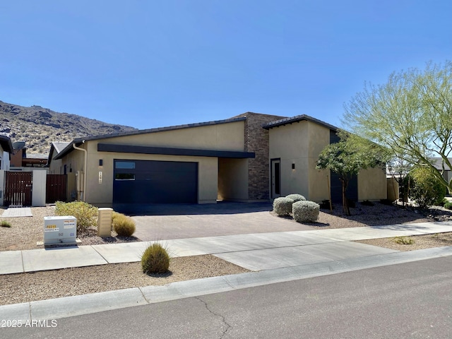 view of front of property with a mountain view, stucco siding, fence, an attached garage, and concrete driveway