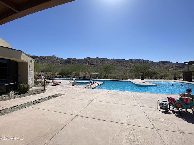 community pool with a mountain view and a patio area