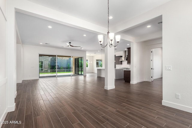 unfurnished living room with dark wood-type flooring, baseboards, recessed lighting, and an inviting chandelier