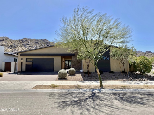 view of front of house featuring a mountain view, stucco siding, driveway, and a garage