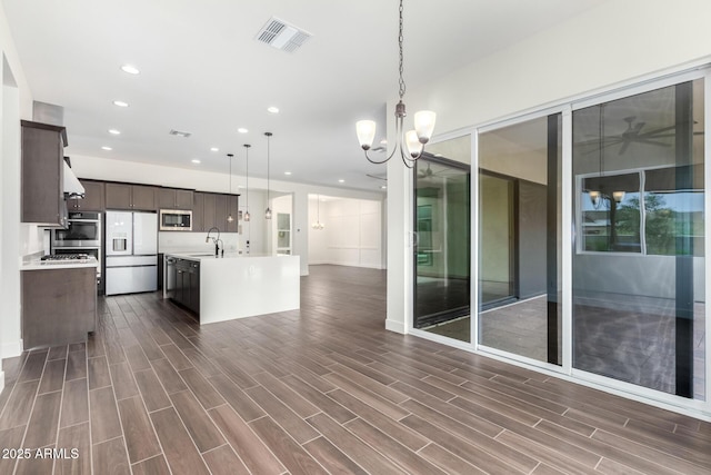 kitchen featuring stainless steel microwave, open floor plan, visible vents, light countertops, and white fridge with ice dispenser