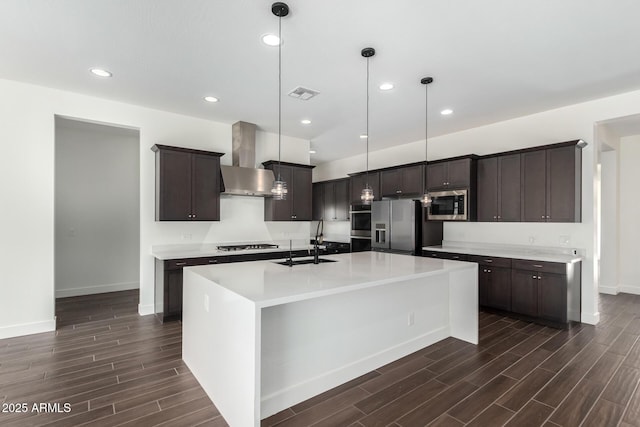 kitchen featuring a sink, dark brown cabinetry, stainless steel appliances, wall chimney exhaust hood, and dark wood-type flooring
