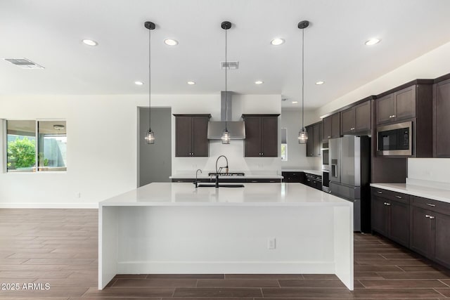 kitchen with wall chimney range hood, appliances with stainless steel finishes, a wealth of natural light, and visible vents