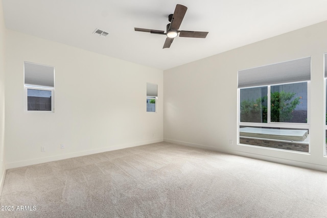 carpeted empty room with baseboards, a ceiling fan, and visible vents