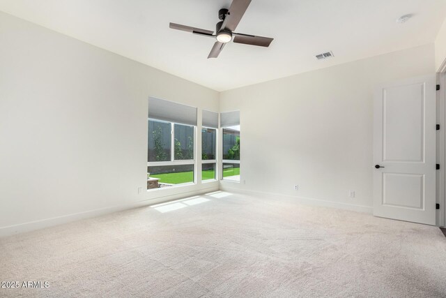 carpeted empty room featuring baseboards, a ceiling fan, and visible vents