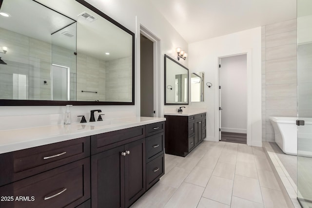 bathroom with a soaking tub, tile patterned floors, a sink, two vanities, and visible vents