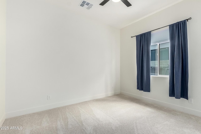 carpeted spare room with visible vents, baseboards, and ceiling fan