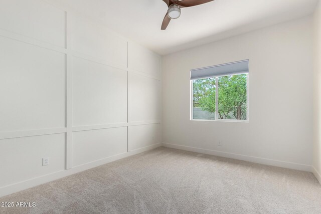 empty room with light colored carpet, baseboards, and a ceiling fan